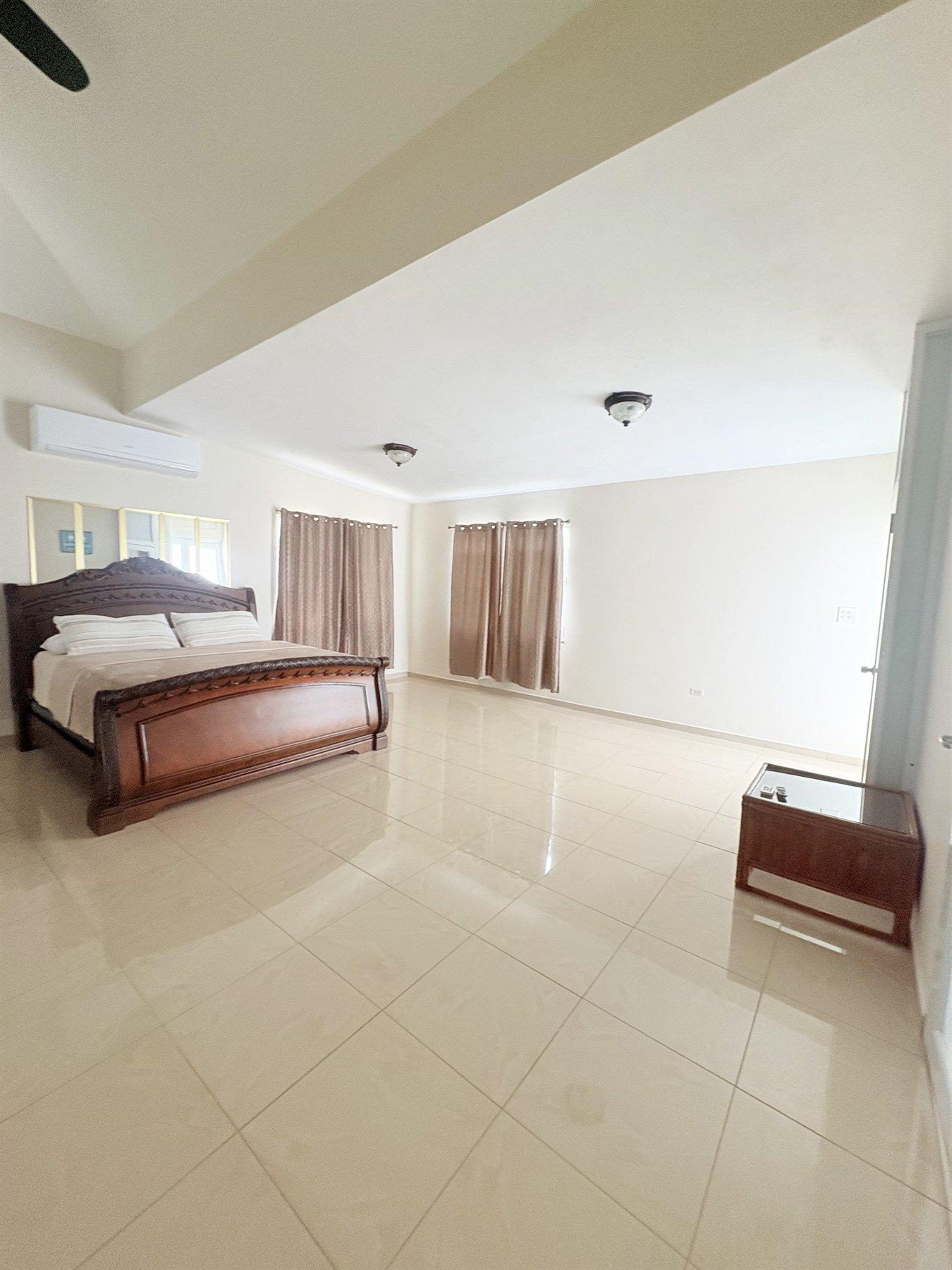 Habitación principal amplia con cama, aire acondicionado y luz natural